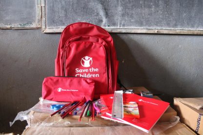 The full school kit on display in a classroom. The kit includes a school bag as well as supplies such as notebooks, chalk, coloured pencils, erasers, rulers and geometry material, pencils, sharpeners, pens, scissors and pencil case.